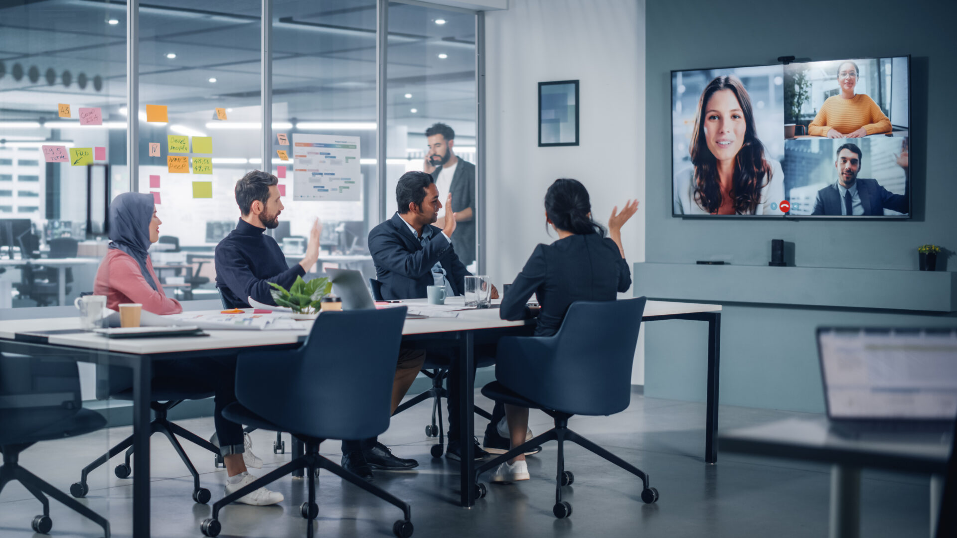 Businesspeople do Video Conference Call with Big Wall TV in Offi
