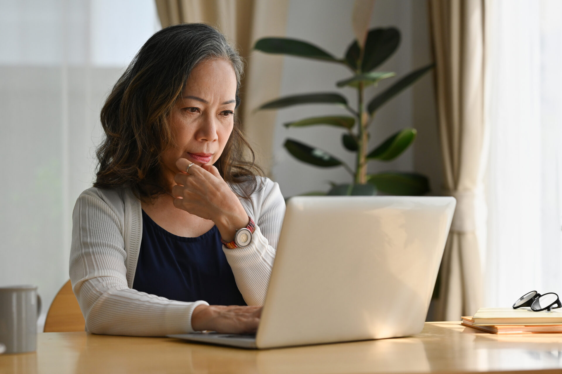 Asian woman work at home using notebook computer with a serious look on her face.