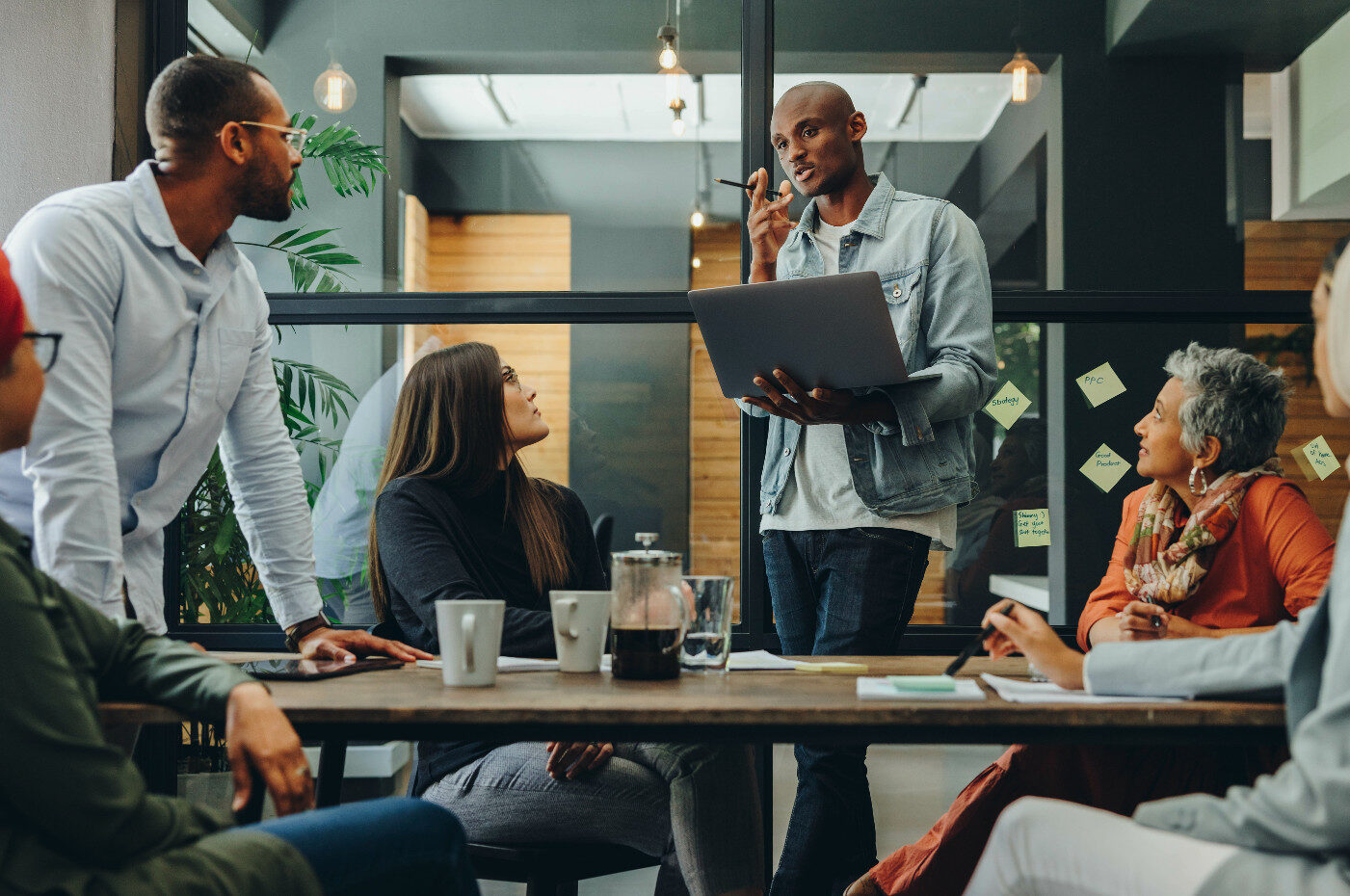 A group of people dressed business casually working together at a table with laptops - collaborating with each other in an office setting
